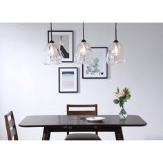 a dining room table with chairs and pictures on the wall above it, along with a vase filled with flowers