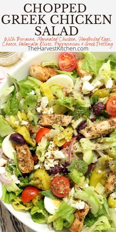 a salad with chicken, lettuce, tomatoes and other vegetables on it in a white bowl