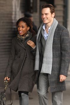 a man and woman are walking down the street together, one is carrying a handbag