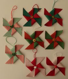 four different types of christmas ornaments hanging from strings on a white wall with green and red stripes