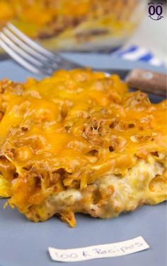 a blue plate topped with a cheesy casserole next to a fork