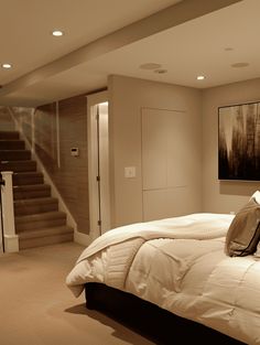 a large bed sitting under a painting on the wall next to a stair case in a bedroom