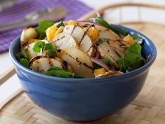 a blue bowl filled with food on top of a wooden table next to a fork