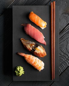 sushi on a black plate with chopsticks