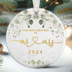 a personalized ornament hanging from a christmas tree with ornaments around it and the words our first christmas as mr and mrs