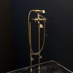 a gold faucet on a marble countertop in a black room with dark walls