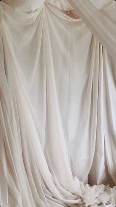 a bed covered in white sheets and drapes