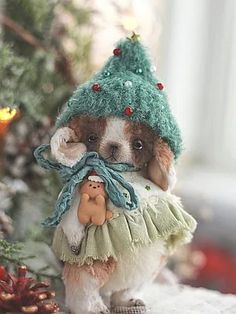 a small dog wearing a green hat and dress next to a christmas ornament