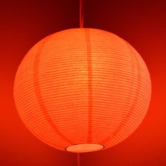 a large orange paper lantern hanging from a ceiling in a room with red walls and flooring