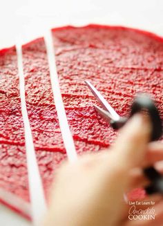 someone is using scissors to cut the red cake