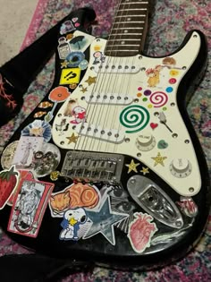 an electric guitar with many stickers on it's body sitting on a carpet