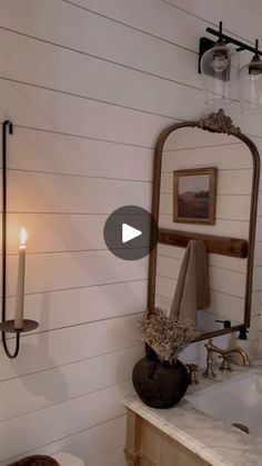 a bathroom with a tub, mirror and candles on the wall in front of it