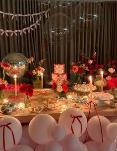 a table topped with lots of white balloons and red flowers next to a mirror ball