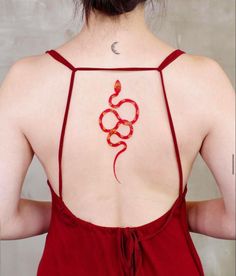 the back of a woman's red dress with a snake tattoo on her chest