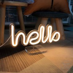 the word hello spelled out in neon lights next to a cell phone on a table