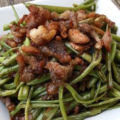 a white plate topped with green beans and meat