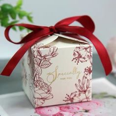 a small box with a red ribbon tied around it on top of a white plate