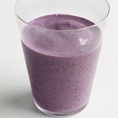 a glass filled with purple liquid sitting on top of a table