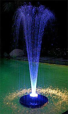 a blue fountain spewing water into the air in a pool at night time