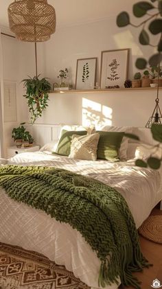 a bed with green and white blankets in a bedroom next to a window filled with potted plants