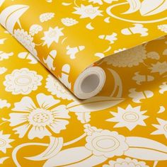 a yellow and white wallpaper with flowers on it's side, next to a roll of tape