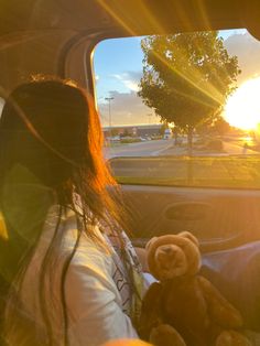 a woman sitting in the back seat of a car with a teddy bear on her lap