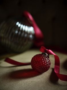 a red ornament sitting on top of a table next to a glass vase