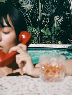 a woman sitting at a table with a red phone in her hand