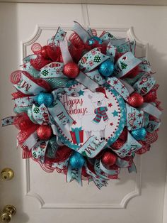 a wreath that says happy holidays hanging on the front door with ornaments around it and an ornament in the shape of a heart