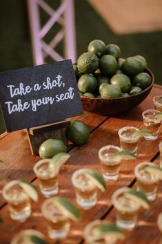 limes and shot glasses on a table with a sign that says take a shot, take your seat