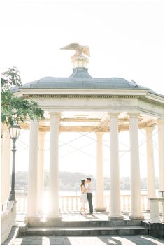 a man and woman standing in front of a gazebo with the sun shining on them