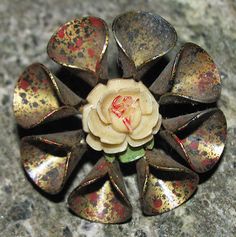 a flower shaped brooch sitting on top of a stone counter covered in gold flecks