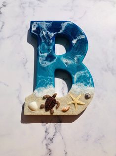 the letter b is made out of sand, shells and starfish on top of it