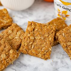 some oatmeal squares are sitting on a marble table next to an orange and yogurt container