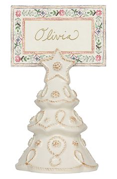 a white ceramic christmas tree with a name tag on it's top and an ornate border around the base