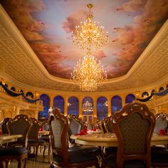 a fancy dining room with chandelier and painted ceiling