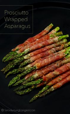 prosciutto wrapped asparagus on a black plate with text overlay