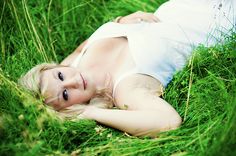 a woman laying in the grass posing for a photo