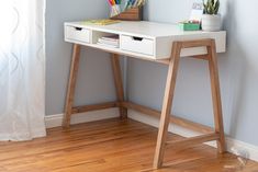 a white desk with two drawers and a wooden shelf on the side next to it