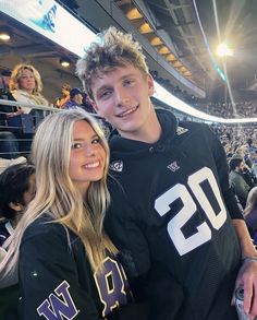 a man and woman standing next to each other in front of an audience at a football game