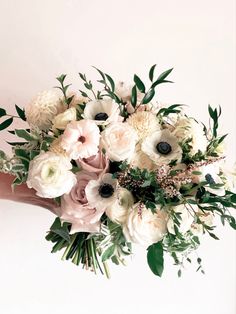 a bouquet of white and pink flowers in someone's hand