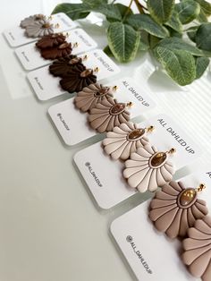 the earrings are lined up in rows on top of each other next to a green plant