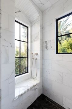 a bathroom with white marble walls and windows