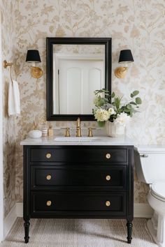 a white toilet sitting next to a black vanity with a mirror on top of it