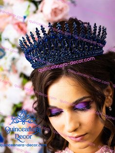 a woman wearing a blue tiara with purple eyeshades and flowers in the background