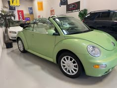 a green car parked in a showroom next to other cars