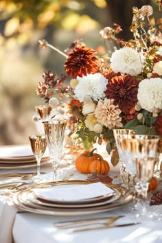 the table is set with white and gold plates, silverware, and orange flowers