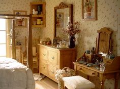 an old fashioned bedroom with floral wallpaper and antique furniture, including a dressing table