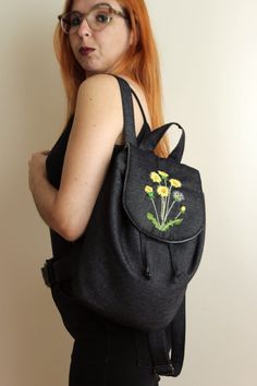 This backpack is embroidered with dandelion flowers. It is made in denim and the lining is in chambray. It is closed by strings and a flap also in denim. Inside it has a pocket. Size: 11,50x8,00x6,50in. Its process starts by drawing the dandelions to hand embroider on the flap. Then the denim fabrics are stitched with a thick interlining. Which in turn are stitched to the lining. Spring Embroidered Backpack, Casual Floral Embroidery Backpack, Casual Floral Embroidered Backpack, Casual Embroidered Everyday Backpack, Casual Everyday Embroidered Backpack, Denim Fabrics, Dandelion Flowers, Dandelion Flower, Pocket Size