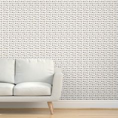 a white couch sitting in front of a wall with dots on it's back